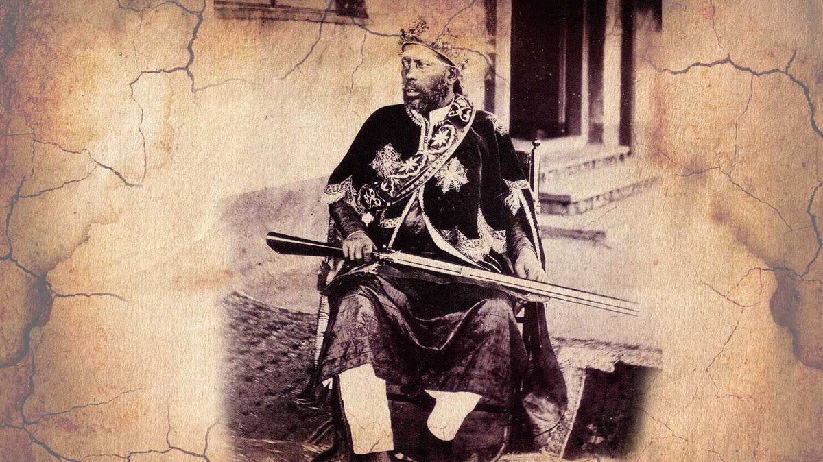 Emperor Menelik II sitting with a rifle